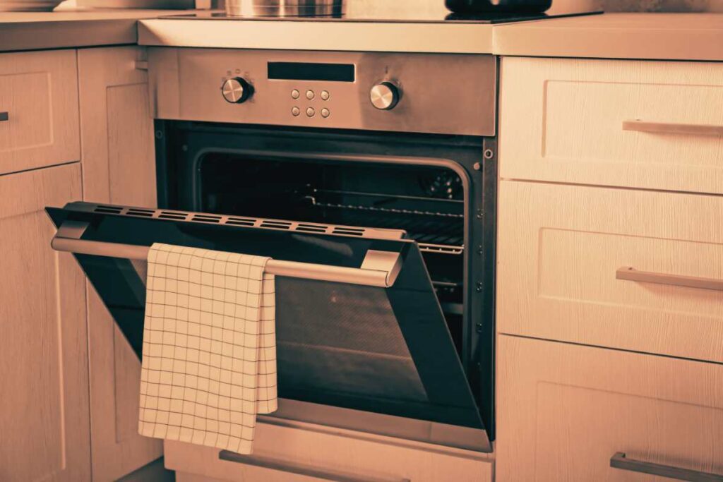Perché non appendere lo strofinaccio allo sportello del forno: i rischi
